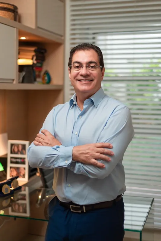 Dr. Roberto Teixeira, sorrindo, em seu consultório
